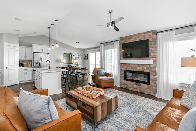 living room with a fireplace, sink, dark hardwood / wood-style floors, vaulted ceiling, and ceiling fan