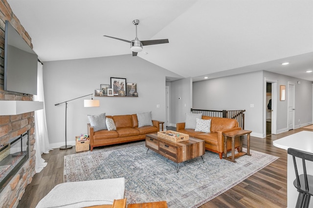 living room with ceiling fan, dark wood-type flooring, vaulted ceiling, and a fireplace