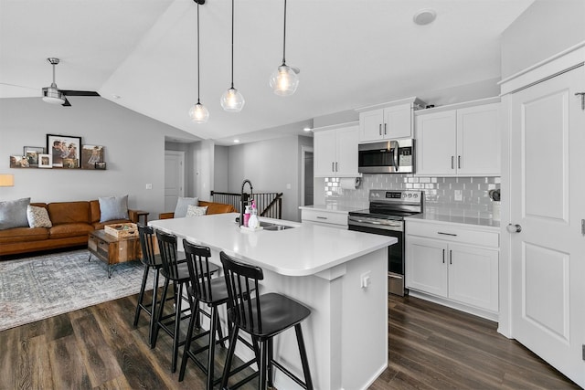 kitchen featuring white cabinets, backsplash, appliances with stainless steel finishes, and a kitchen island with sink