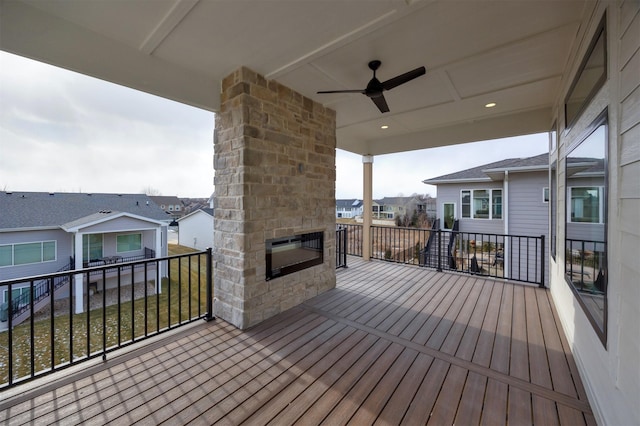 wooden terrace featuring a residential view, a fireplace, and a ceiling fan