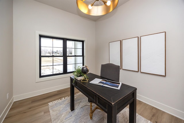 office with baseboards, an inviting chandelier, and wood finished floors