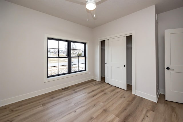 unfurnished bedroom featuring ceiling fan, a closet, and light wood-type flooring