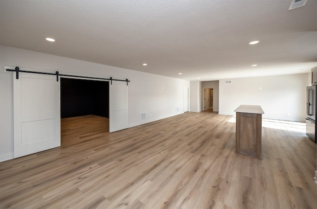 interior space featuring recessed lighting, visible vents, a barn door, and light wood finished floors