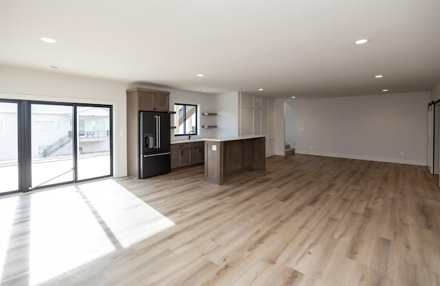kitchen featuring a center island, high end black refrigerator, light wood-style flooring, and open floor plan