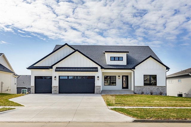 modern farmhouse style home with a garage, a front yard, stone siding, board and batten siding, and driveway