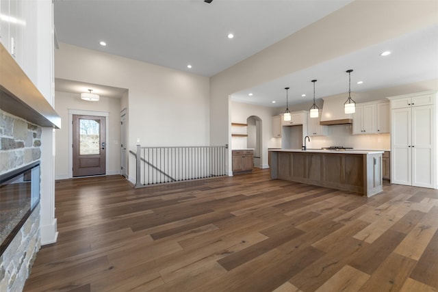 kitchen featuring a spacious island, white cabinetry, dark hardwood / wood-style flooring, sink, and hanging light fixtures