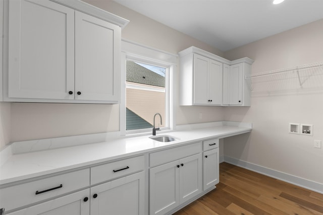 clothes washing area featuring washer hookup, sink, hardwood / wood-style floors, and cabinets