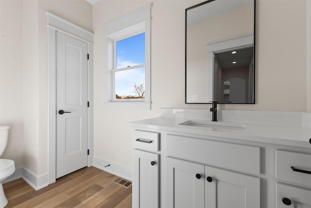 bathroom featuring toilet, vanity, and wood-type flooring