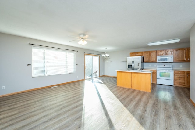 kitchen with a center island, white appliances, light hardwood / wood-style flooring, hanging light fixtures, and ceiling fan with notable chandelier