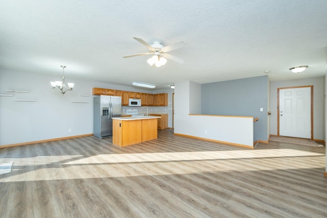 kitchen featuring a kitchen island, decorative light fixtures, sink, stainless steel fridge with ice dispenser, and light wood-type flooring