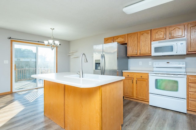 kitchen featuring decorative light fixtures, an island with sink, dark hardwood / wood-style floors, and white appliances