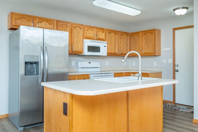 kitchen with hardwood / wood-style floors, white appliances, and a center island with sink