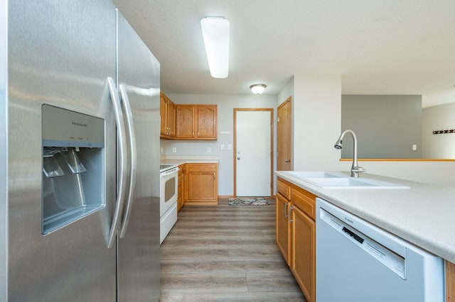 kitchen featuring light wood-type flooring, sink, and white appliances