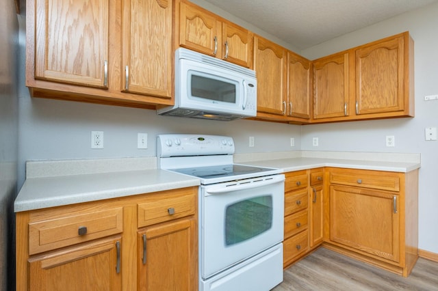 kitchen with light wood-type flooring and white appliances