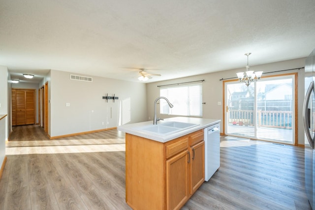 kitchen featuring pendant lighting, dishwasher, light hardwood / wood-style floors, sink, and a kitchen island with sink