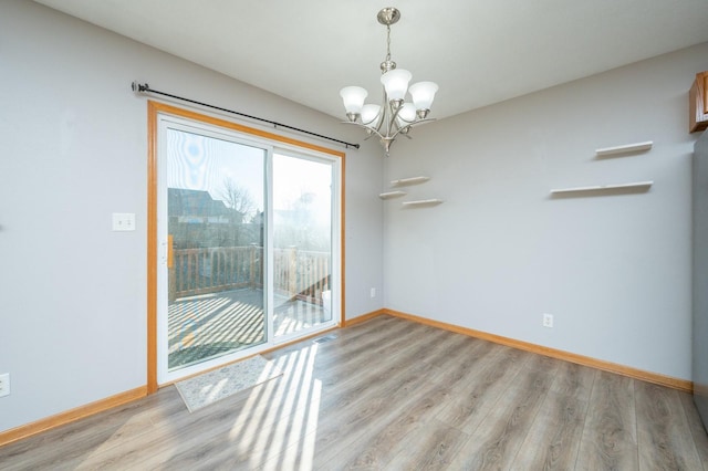 empty room featuring light wood-type flooring and a chandelier