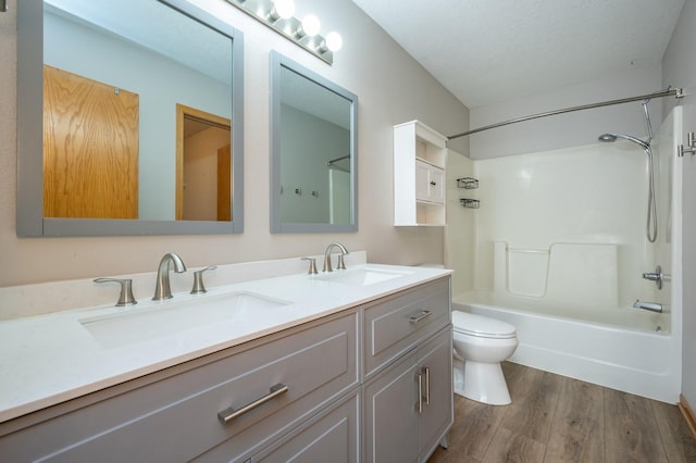 full bathroom with a textured ceiling, wood-type flooring, vanity, toilet, and shower / bathtub combination