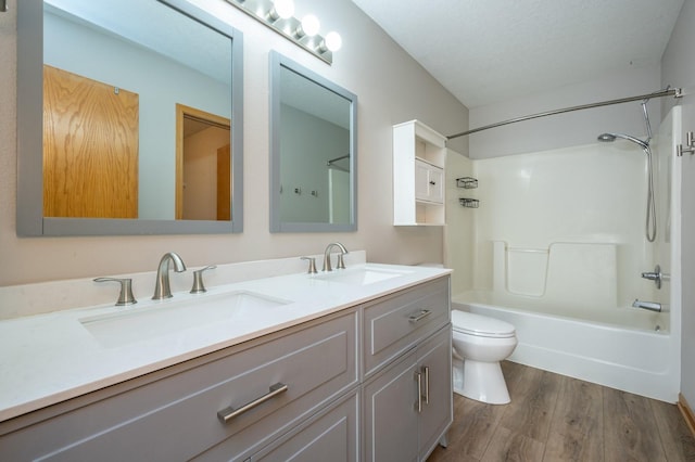 bathroom featuring a sink, double vanity, toilet, and wood finished floors