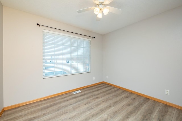 spare room featuring baseboards, light wood-style floors, ceiling fan, and visible vents
