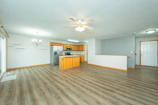 kitchen featuring a textured ceiling, stainless steel appliances, light wood-style flooring, and open floor plan