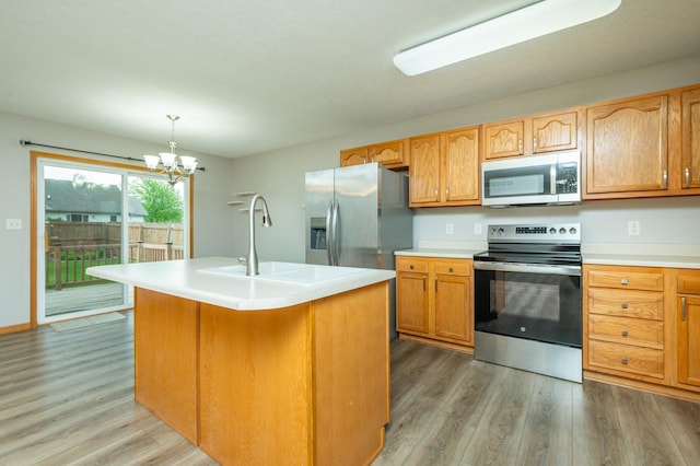 kitchen featuring light countertops, a sink, light wood finished floors, a notable chandelier, and stainless steel appliances