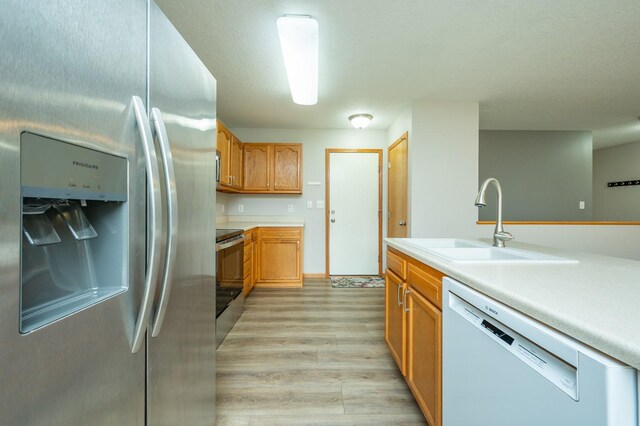 kitchen with a sink, light countertops, stainless steel appliances, and light wood finished floors
