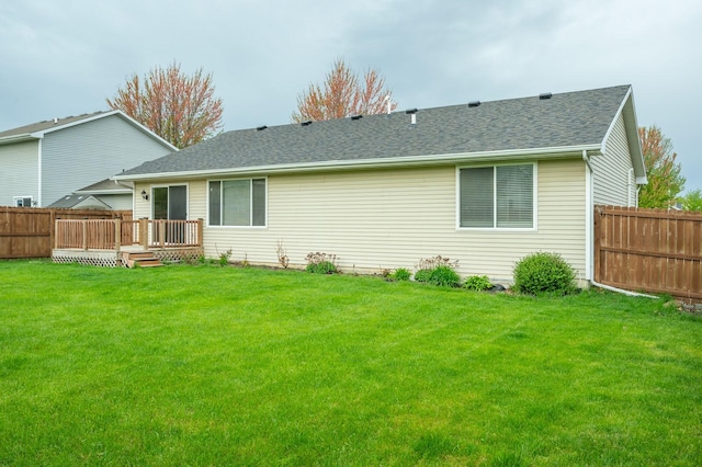 rear view of house featuring a shingled roof, fence, a yard, and a wooden deck