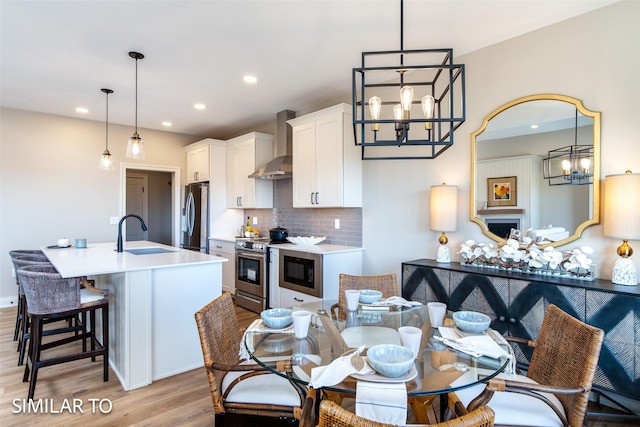 kitchen featuring white cabinetry, appliances with stainless steel finishes, decorative backsplash, wall chimney exhaust hood, and sink