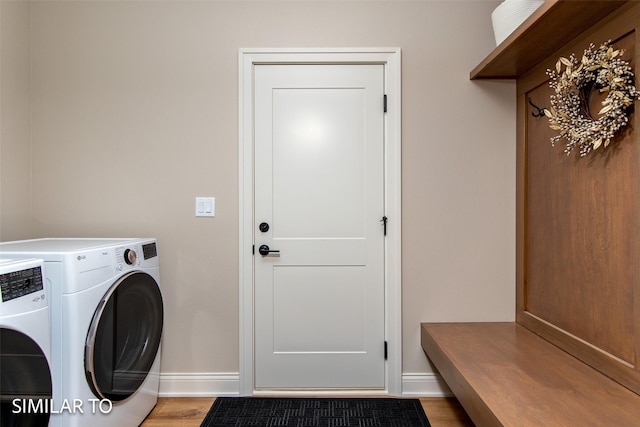 clothes washing area with separate washer and dryer and light hardwood / wood-style flooring