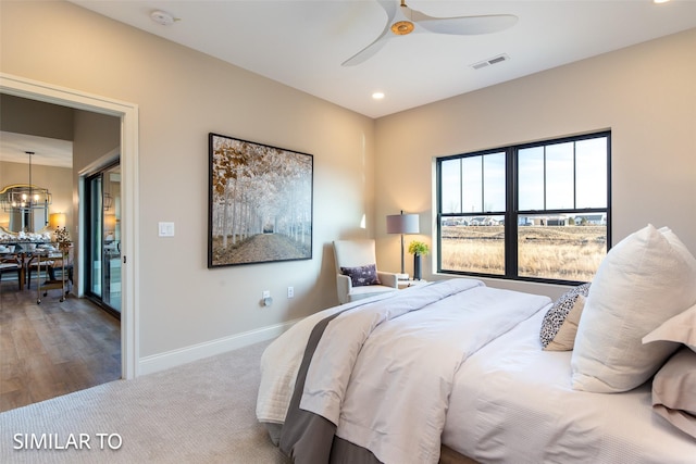 carpeted bedroom with ceiling fan with notable chandelier