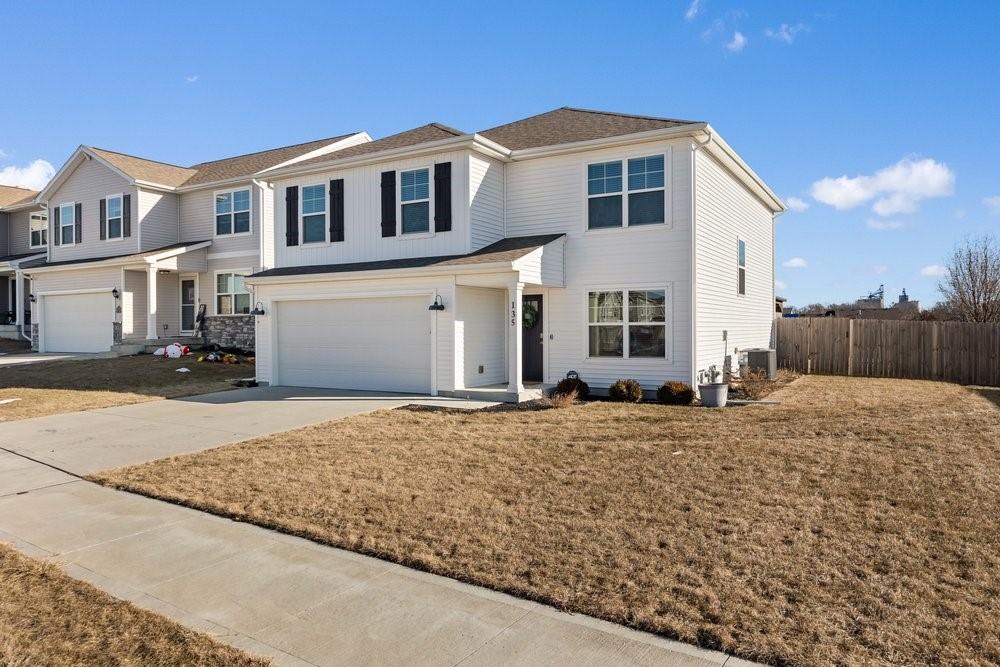 view of property with central AC unit, a front yard, and a garage