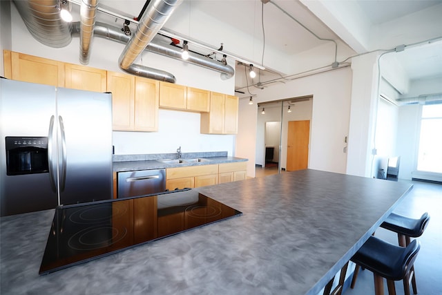 kitchen featuring decorative light fixtures, sink, appliances with stainless steel finishes, light brown cabinets, and concrete flooring