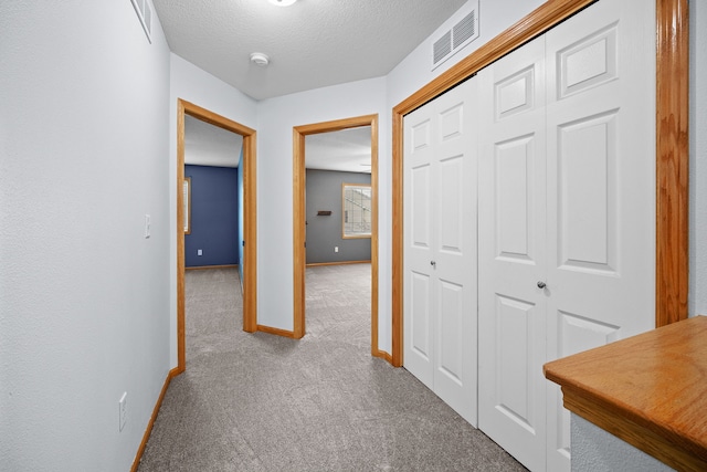 hall with carpet floors and a textured ceiling