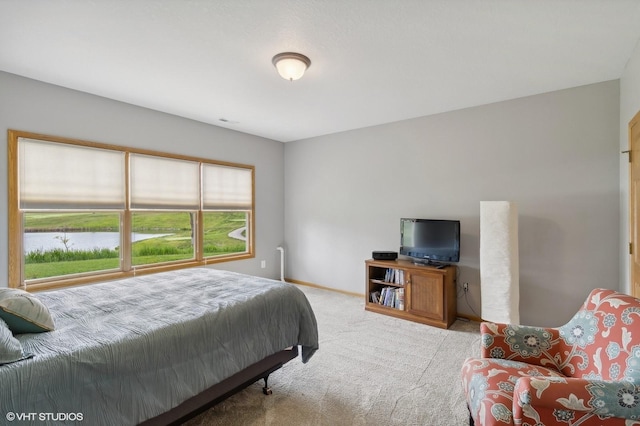 bedroom featuring light carpet and a water view