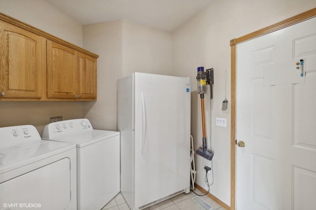 laundry area with cabinets, light tile patterned floors, and washer and clothes dryer