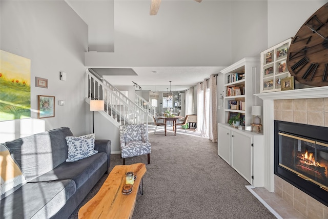 carpeted living room featuring a tile fireplace and a high ceiling