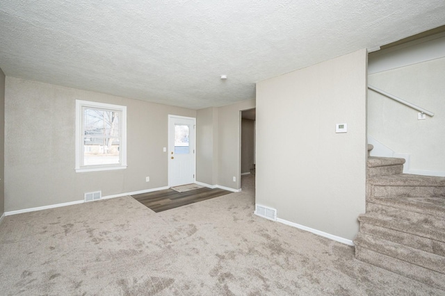 foyer entrance with a textured ceiling and carpet flooring