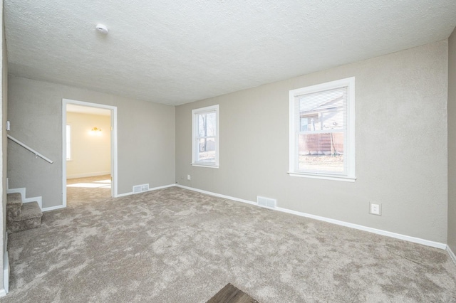 carpeted spare room featuring a textured ceiling