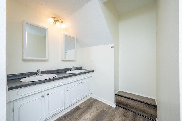 bathroom with lofted ceiling, hardwood / wood-style flooring, and vanity