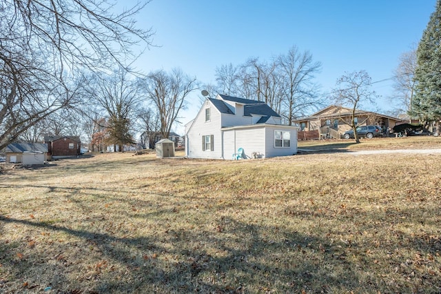 view of side of property with a shed and a yard