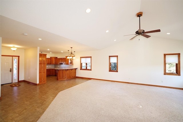 unfurnished living room featuring vaulted ceiling, a wealth of natural light, and ceiling fan with notable chandelier