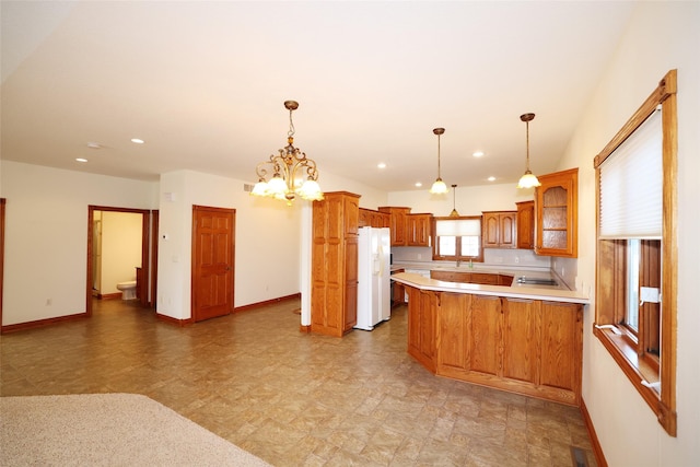 kitchen featuring kitchen peninsula, hanging light fixtures, a breakfast bar area, white fridge with ice dispenser, and a chandelier