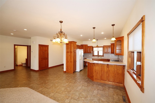 kitchen featuring kitchen peninsula, a breakfast bar area, a notable chandelier, decorative light fixtures, and white refrigerator with ice dispenser