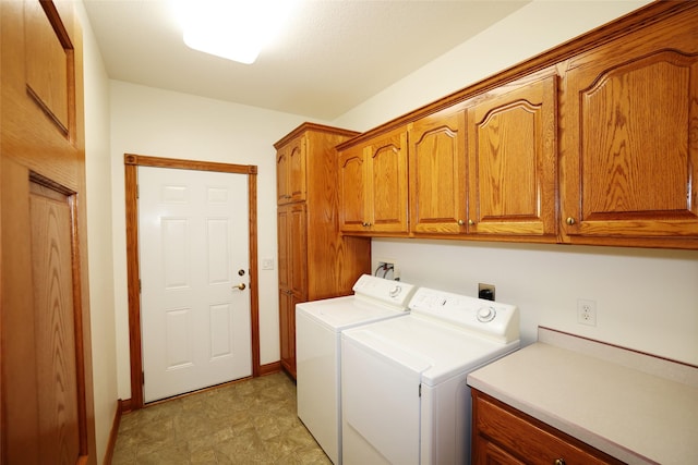 clothes washing area with separate washer and dryer and cabinets