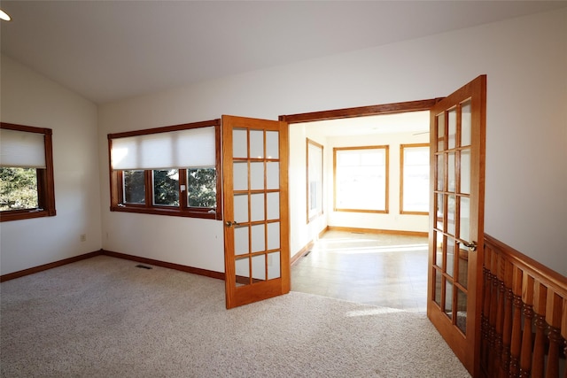 spare room with light colored carpet, french doors, and vaulted ceiling