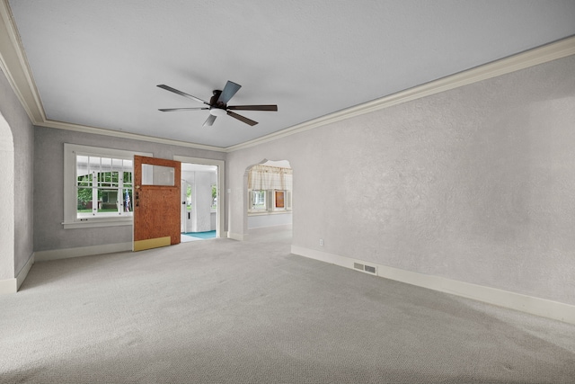 1001 42nd St, Des Moines, IA 50311 - carpeted spare room with crown molding, baseboards, a ceiling fan, a textured wall, and arched walkways