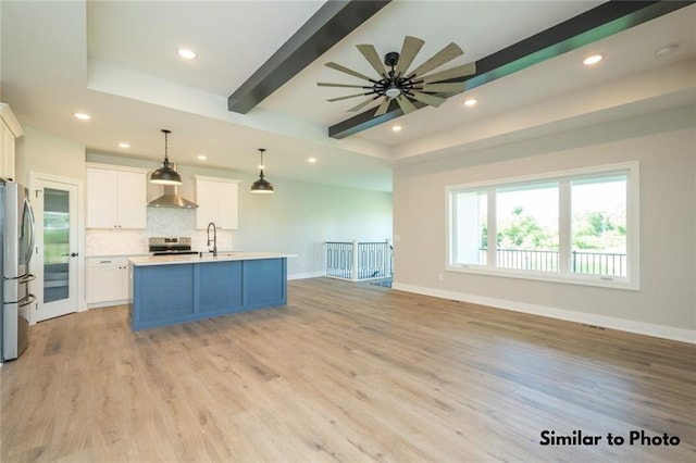 kitchen with decorative light fixtures, sink, white cabinetry, an island with sink, and stainless steel fridge