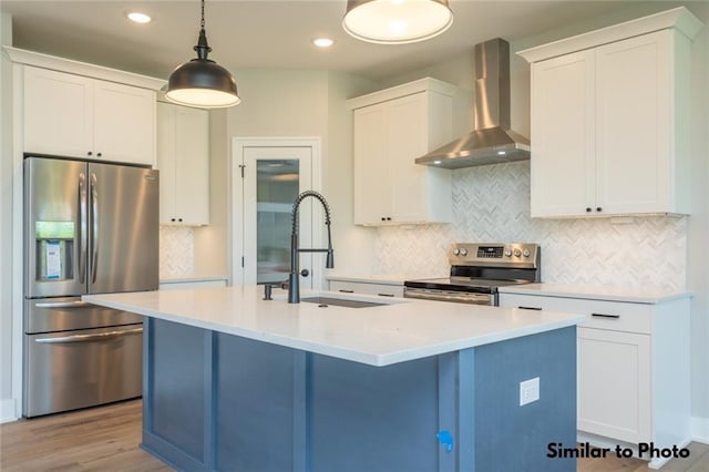 kitchen with pendant lighting, white cabinets, wall chimney range hood, and appliances with stainless steel finishes