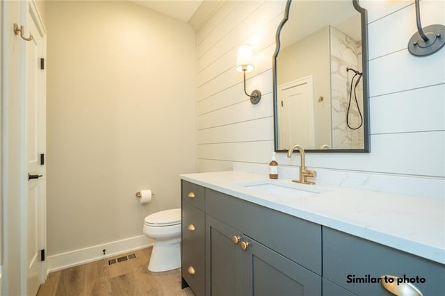 bathroom featuring toilet, vanity, a shower, and hardwood / wood-style flooring