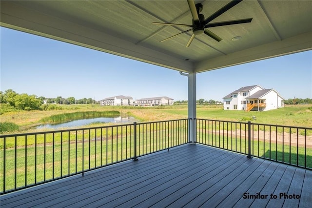 deck featuring ceiling fan, a water view, and a yard